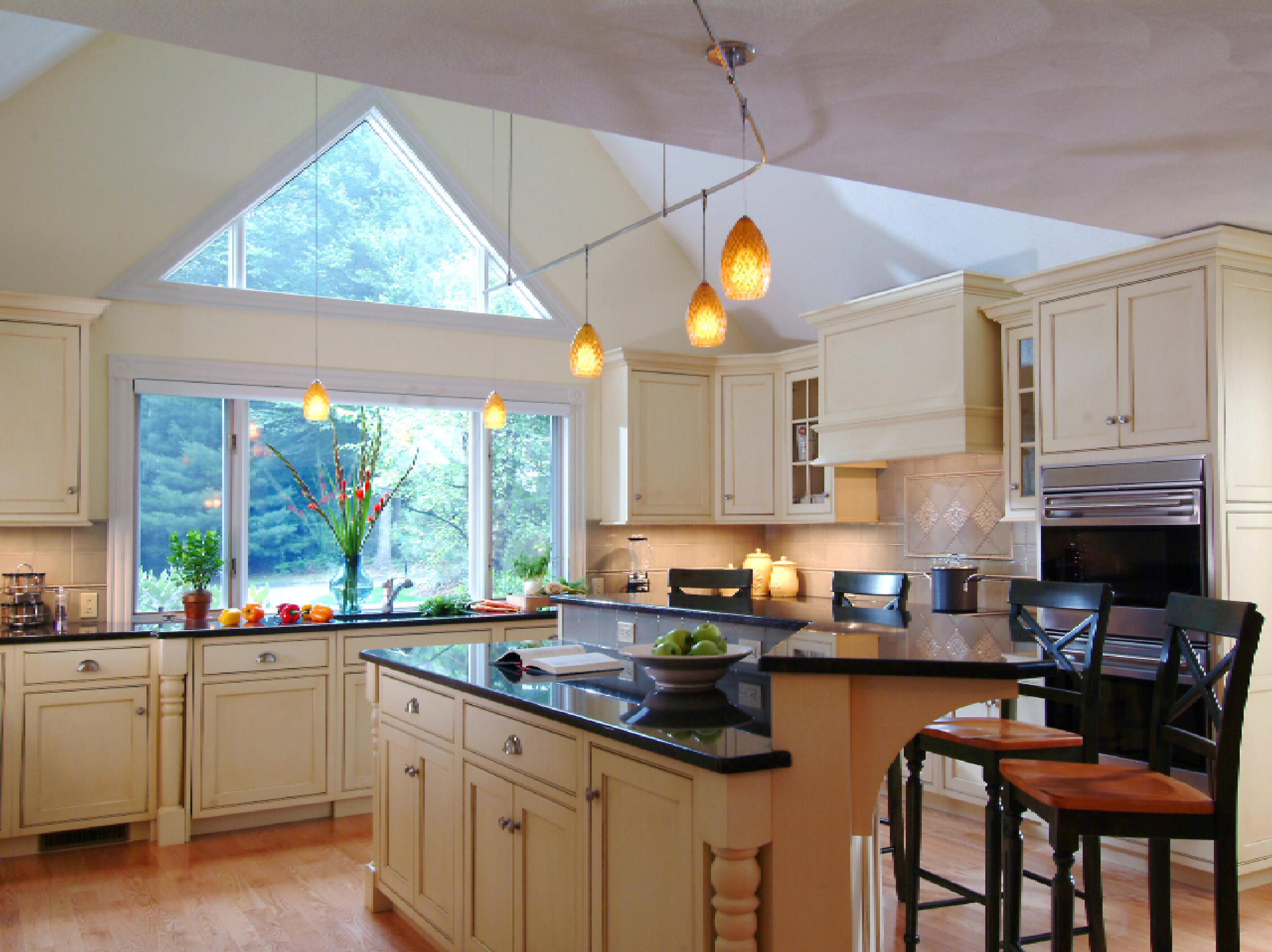 A spacious kitchen with wooden cabinets, a central island with a built-in wine rack, stainless steel appliances, and green tile backsplash. natural light illuminates the room.